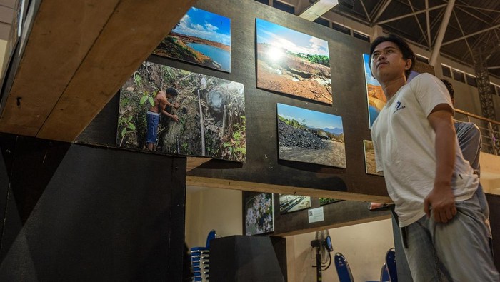 Pengunjung berjalan di belakang foto-foto pada pameran foto Hari Anti Tambang (Hatam) di Palu, Sulawesi Tengah. Minggu (26/5/2024). Dalam rangka memperingati Hari Anti Tambang yang jatuh pada 29 Mei, pameran yang diinisiasi Jaringan Advokasi Tambang (Jatam) Sulteng itu juga untuk menunjukkan kepada khalayak tentang dampak buruk dari industri ekstraktif baik terhadap kesehatan maupun terhadap lingkungan. ANTARA FOTO/Basri Marzuki/rwa.