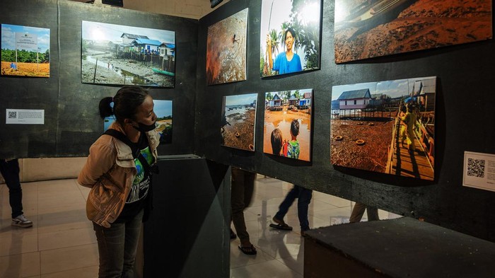 Pengunjung berjalan di belakang foto-foto pada pameran foto Hari Anti Tambang (Hatam) di Palu, Sulawesi Tengah. Minggu (26/5/2024). Dalam rangka memperingati Hari Anti Tambang yang jatuh pada 29 Mei, pameran yang diinisiasi Jaringan Advokasi Tambang (Jatam) Sulteng itu juga untuk menunjukkan kepada khalayak tentang dampak buruk dari industri ekstraktif baik terhadap kesehatan maupun terhadap lingkungan. ANTARA FOTO/Basri Marzuki/rwa.