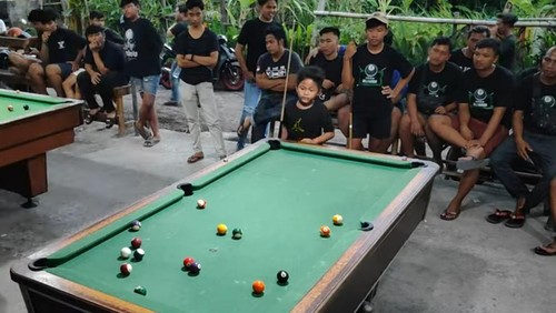 Pebiliar cilik asal Gianyar, Dewa Gede Tria Nandrawan alias Ode Nandra, saat mengikuti turnamen biliar melawan pemain dewasa. (Dok. Dewa Made Artawan)