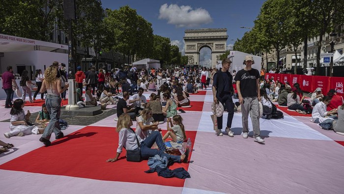 People eat their lunches as part of a giant picnic on the Champs-Elysées, in front of the Arc de Triomphe, organized by the Comité Champs-Élysées, Sunday, May 26, 2024 in Paris. (AP Photo/Aurelien Morissard)