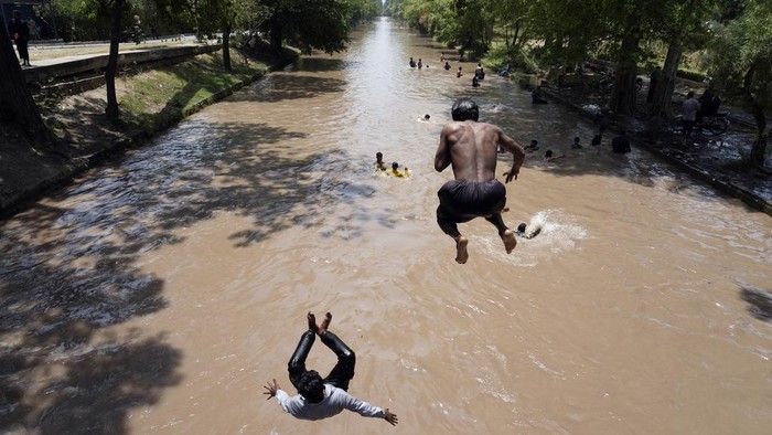 Pakistani youths cool themselves off in a canal during hot weather in Lahore, Pakistan, Sunday, May 26, 2024. (AP Photo/K.M. Chaudary)