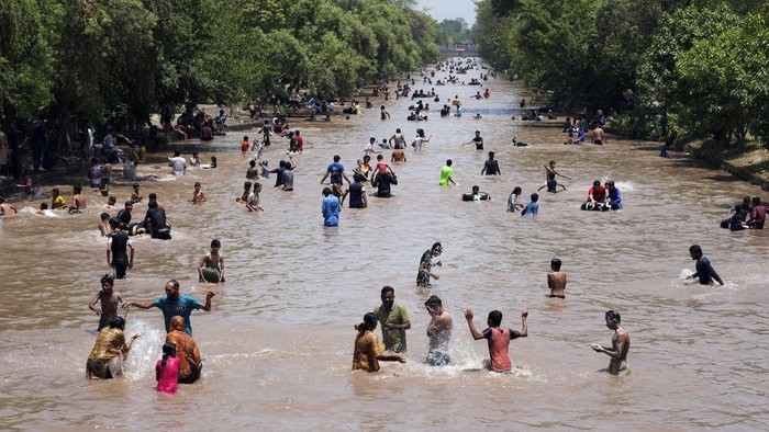 Pakistani youths cool themselves off in a canal during hot weather in Lahore, Pakistan, Sunday, May 26, 2024. (AP Photo/K.M. Chaudary)