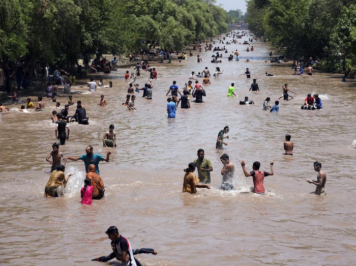 Pakistani youths cool themselves off in a canal during hot weather in Lahore, Pakistan, Sunday, May 26, 2024. (AP Photo/K.M. Chaudary)