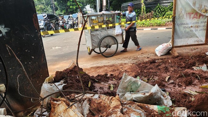Warga melintasi proyek galian kabel fiber optik di Jl Wijaya I, Jakarta Selatan, Selasa (28/5/2024).