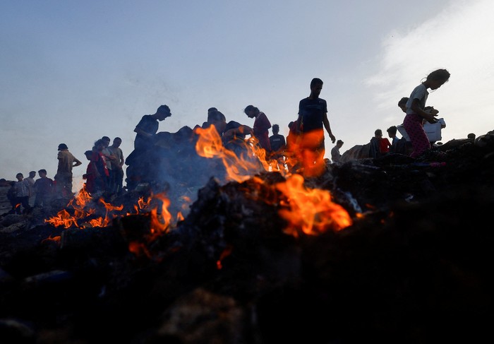 Palestinians search for food among burnt debris in the aftermath of an Israeli strike on an area designated for displaced people, in Rafah in the southern Gaza Strip, May 27, 2024. REUTERS/Mohammed Salem