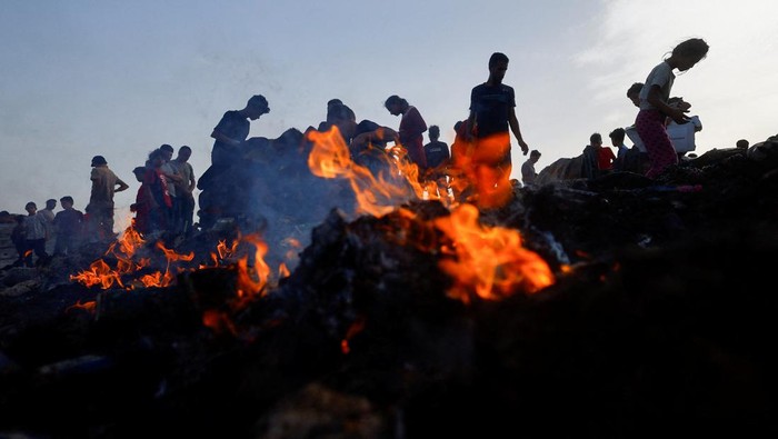 Palestinians search for food among burnt debris in the aftermath of an Israeli strike on an area designated for displaced people, in Rafah in the southern Gaza Strip, May 27, 2024. REUTERS/Mohammed Salem