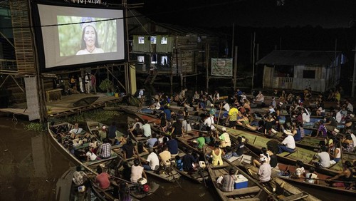 Spectators watch a film from boats during the Muyuna Floating Film Festival, showcasing films from countries with tropical forests, in the Belen neighborhood of Iquitos, Peru, on Sunday, May 26, 2024. (AP Photo/Rodrigo Abd)