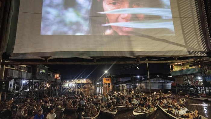 Spectators watch a film from boats during the Muyuna Floating Film Festival, showcasing films from countries with tropical forests, in the Belen neighborhood of Iquitos, Peru, on Sunday, May 26, 2024. (AP Photo/Rodrigo Abd)