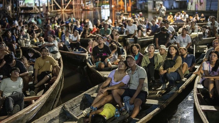 Spectators watch a film from boats during the Muyuna Floating Film Festival, showcasing films from countries with tropical forests, in the Belen neighborhood of Iquitos, Peru, on Sunday, May 26, 2024. (AP Photo/Rodrigo Abd)