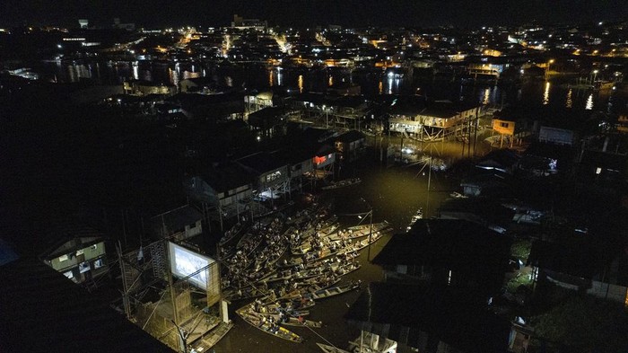 Spectators watch a film from boats during the Muyuna Floating Film Festival, showcasing films from countries with tropical forests, in the Belen neighborhood of Iquitos, Peru, on Sunday, May 26, 2024. (AP Photo/Rodrigo Abd)