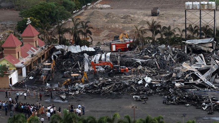 Sisa-sisa Kebakaran Area Bermain di India yang Tewaskan 27 Orang Machines move debris following a fire in a gaming zone in Rajkot, in the western state of Gujarat, India, May 26, 2024. REUTERS/Amit Dave