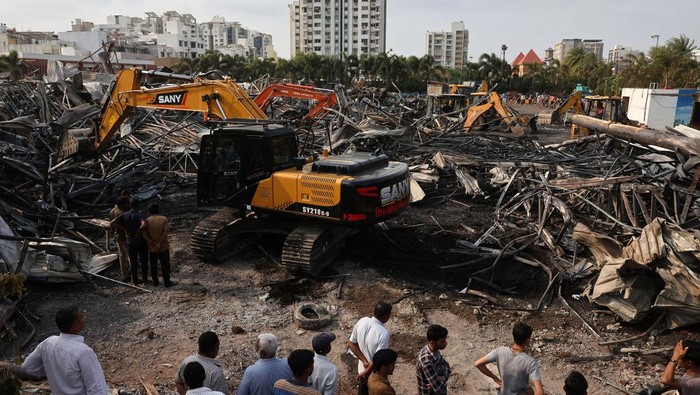 Sisa-sisa Kebakaran Area Bermain di India yang Tewaskan 27 Orang Machines move debris following a fire in a gaming zone in Rajkot, in the western state of Gujarat, India, May 26, 2024. REUTERS/Amit Dave