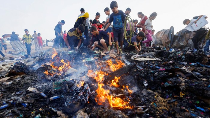 Palestinians search for food among burnt debris in the aftermath of an Israeli strike on an area designated for displaced people, in Rafah in the southern Gaza Strip, May 27, 2024. REUTERS/Mohammed Salem