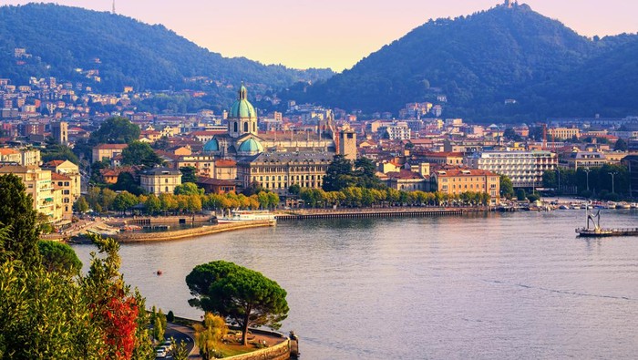 Como city historical town center and Alps mountains on Lake Como, Italy, in warm sunset light