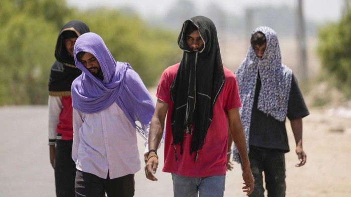 People cover their heads with scarves as protection against the harsh sun on a hot summer day in Jammu, India, Tuesday, May.28, 2024. (AP Photo/Channi Anand)