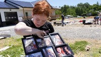 Warga mengais barang-barang di puing-puing rumahnya yang ambruk di Madisonville, Kentucky.