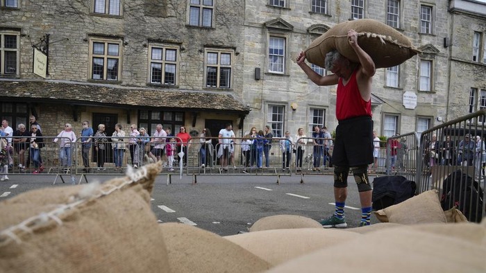 Potret Lomba Lari Ekstrem Sambil Pikul Karung Wol di Inggris Participants race with a woolsack on their shoulders during the annual Tetbury Woolsack Races in Tetbury, Gloucestershire, England, Monday, May 27, 2024. The annual Woolsack Races that take place in the Wiltshire wool-town of Tetbury. Every year teams of men, women and children carry sacks of British wool, 60-pound (27 kg) for men's races and 35 pounds (16 kg) for women's, up and down the Gumstool Hill with course of 240 yards (220 meters). An official Woolsack Races has been going since 1972, with world records entered in the 'Guinness Book of Records'. (AP Photo/Kin Cheung)