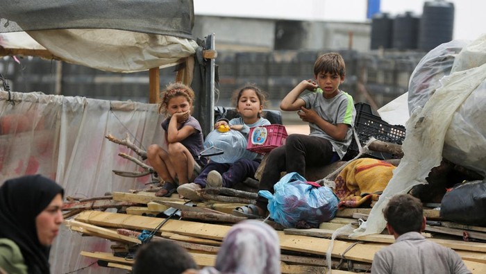 Children look on, as Palestinians travel on foot along with their belongings as they flee Rafah due to an Israeli military operation, in Rafah, in the southern Gaza Strip, May 28, 2024. REUTERS/Hatem Khaled