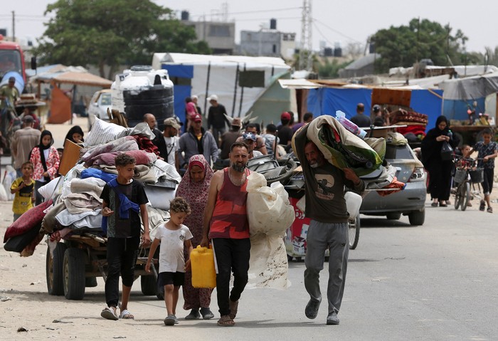 Children look on, as Palestinians travel on foot along with their belongings as they flee Rafah due to an Israeli military operation, in Rafah, in the southern Gaza Strip, May 28, 2024. REUTERS/Hatem Khaled