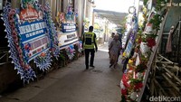 Sejumlah karangan bunga duka dari pejabat berjajar hingga ke gang masuk rumah duka.