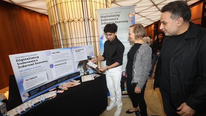 Rehan Bharwani (kiri) siswa kelas 11 Jakarta International School menjelaskan presentasi nya mengenai pentingnya inklusivitas perekonomian informal di Indonesia guna meningkatkan pemasukan negara kepada Founder of JSS Carolyn Tiemann (dua kiri) pada ajang Innovating for Impact yang diadakan oleh Jakarta Scholars Symposium di Energy Building, SCBD, Jakarta, Rabu (29/5/2024). Rehan mempusatkan presentasinya pada transformasi pembayaran secara digital yang terintegrasi dan mudah diakses secara nasional agar terjangkau oleh pemilik bisnis.