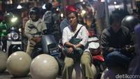 Seorang warga terlihat menunggu ojek online untuk melanjutkan pulang usai bekerja.