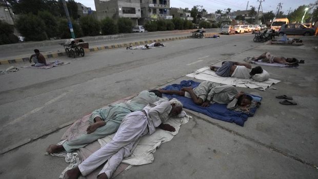 Laborers sleep on the roadside during an early hot summer morning in Karachi, Pakistan, Wednesday, May 29, 2024. Pakistani port city Karachi and some other parts of the country continued to experience heat wave these days. (AP Photo/Fareed Khan)