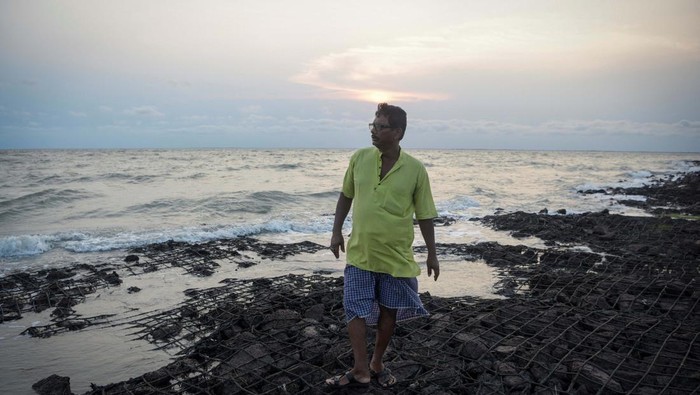 Potret Pulau Ghoramara di India yang Terancam Hilang Debasish Paul, 62, a volunteer who works independently on environmental awareness and protection of the island, stands on an embankment built with boulders to prevent erosion, on the western part of Ghoramara Island in the Sundarbans, West Bengal, India, May 17, 2024. Situated 150 kilometres (around 94 miles) south of Kolkata, media has dubbed Ghoramara the 'sinking island'. It has lost nearly half of its area to soil erosion in the last two decades and could completely disappear within a few more decades if a solution is not found. In the decade of 2020, the population has fallen to around 4,000 from 7,000. REUTERS/Avijit Ghosh SEARCH