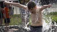 Seorang anak memandikan seluruh badannya dengan air sungai Neglinnaya di Moskow, Rusia, Rabu (29/5/2024).