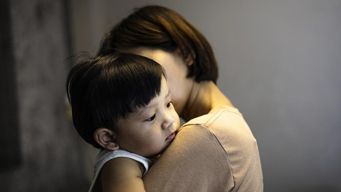 Mother carries the child in her arms. Little boy lies in his mothers shoulder. Sad son hugs mom.