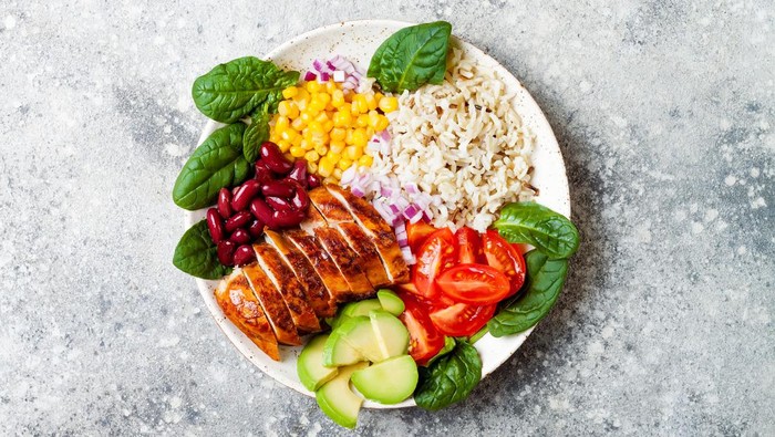 Homemade Mexican chicken burrito bowl with rice, beans, corn, tomato, avocado, spinach. Taco salad lunch bowl