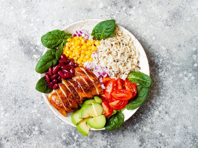 Homemade Mexican chicken burrito bowl with rice, beans, corn, tomato, avocado, spinach. Taco salad lunch bowl