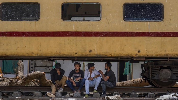Roadside vendors rest in the shade beneath a stationary train coach on a hot summer day in Mumbai, India, Thursday, May 30, 2024. (AP Photo/Rafiq Maqbool)