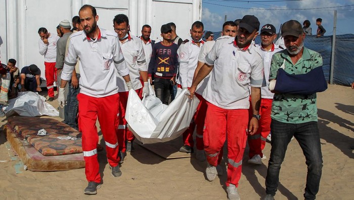 Palestinian members of Palestine Red Crescent Society (PRCS) react as they gather near the bodies of their two fellow paramedics, who according to medics, were killed when an ambulance on a mission to rescue people was hit in an Israeli strike, during their funeral in Rafah in the southern Gaza Strip, May 30, 2024. REUTERS/Hatem Khaled
