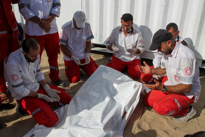 Palestinian members of Palestine Red Crescent Society (PRCS) react as they gather near the bodies of their two fellow paramedics, who according to medics, were killed when an ambulance on a mission to rescue people was hit in an Israeli strike, during their funeral in Rafah in the southern Gaza Strip, May 30, 2024. REUTERS/Hatem Khaled