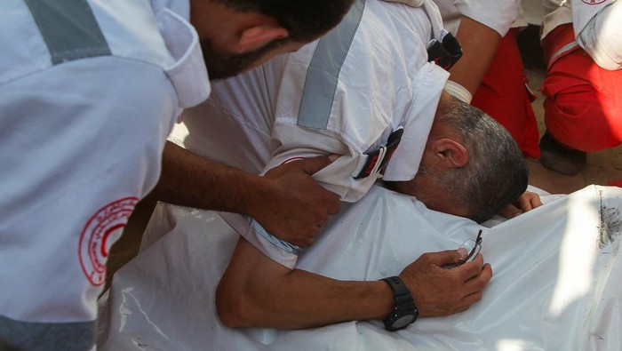 Palestinian members of Palestine Red Crescent Society (PRCS) react as they gather near the bodies of their two fellow paramedics, who according to medics, were killed when an ambulance on a mission to rescue people was hit in an Israeli strike, during their funeral in Rafah in the southern Gaza Strip, May 30, 2024. REUTERS/Hatem Khaled