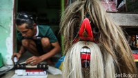 Selain membuat dan menjual mainan bus dan kereta, Yayat juga menjajakan topeng barongan asal Kediri.