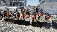 Para relawan memasak makanan di dapur umum yang berada di antara puing-puing bangunan di Khan Younis di selatan Jalur Gaza, 30 Mei 2024.  