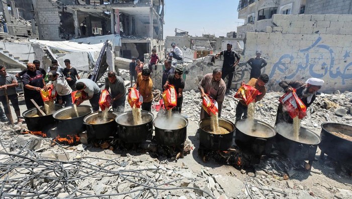 Palestinians eat food cooked by a charity kitchen near houses destroyed in the Israeli military offensive, in Khan Younis in the southern Gaza Strip, May 30, 2024. REUTERS/Ramadan Abed