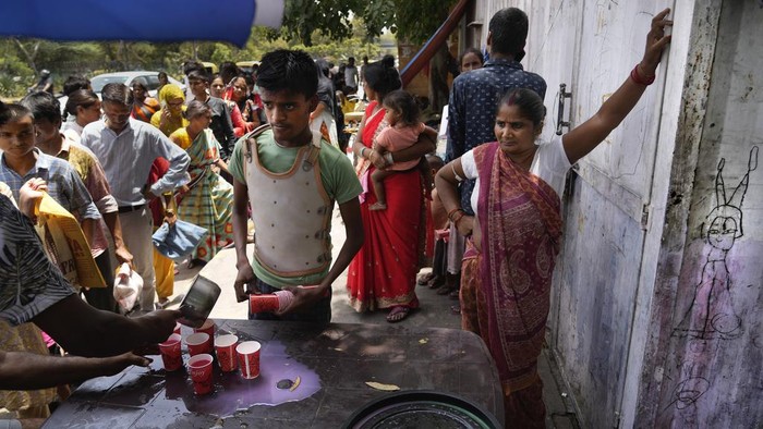 Passersby stand in a queue to receive a cup of cold drink distributed by a non-governmental organization as a heat wave grips the Indian capital New Delhi, India, Thursday, May 30, 2024. (AP Photo/Manish Swarup)