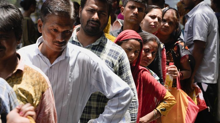 Passersby stand in a queue to receive a cup of cold drink distributed by a non-governmental organization as a heat wave grips the Indian capital New Delhi, India, Thursday, May 30, 2024. (AP Photo/Manish Swarup)