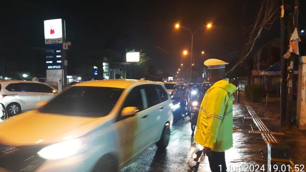 Polisi melakukan pengaturan arus lalu lintas di Jalan RA Kartini, Depok yang mengalami macet imbas banjir.