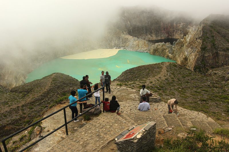 Pengunjung berfoto di Danau Kelimutu, Gunung Kelimutu, Kabupaten Ende, Nusa Tenggara Timur, Minggu (2/6/2024). Gunung api jenis strato yang memiliki tiga danau kawah, yakni Kawah I (Tiwu Ata Polo), Kawah II (Tiwu Koofai Nuwamuri), dan Kawah III (Tiwu Ata Bupu) tersebut mengalami kenaikan status dari level I atau normal ke level II atau waspada pada tanggal 24 Mei 2024 karena adanya perubahan yang signifikan warna air danau kawah I maupun kenampakan dan sebaran belerang di permukaan air danau kawah II yang semakin intensif. ANTARA FOTO/Mega Tokan/sgd/foc.