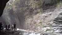 Tebing batu yang besar dan tinggi yang membentuk lorong di Curug Ibun Pelangi.