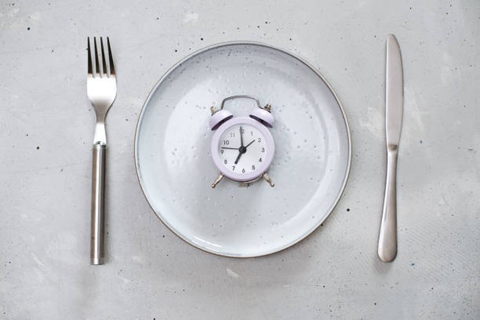 breakfast time concept with alarm clock plate, fork, knife, spoon,