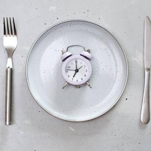 breakfast time concept with alarm clock plate, fork, knife, spoon,