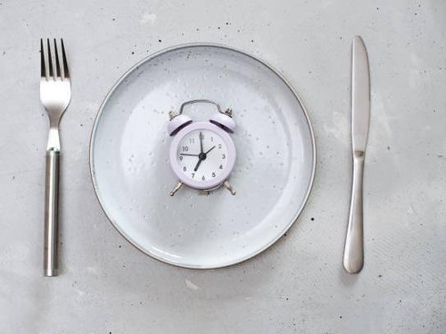 breakfast time concept with alarm clock plate, fork, knife, spoon,