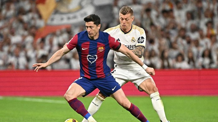 Barcelonas Polish forward #09 Robert Lewandowski vies with Real Madrids German midfielder #08 Toni Kroos during the Spanish league football match between Real Madrid CF and FC Barcelona at the Santiago Bernabeu stadium in Madrid on April 21, 2024. (Photo by JAVIER SORIANO / AFP)