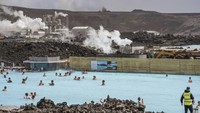 Orang-orang berenang dengan latar belakang Gunung Berapi Grindavik yang memuntahkan lava di Pemandian Blue Lagoon, Islandia, Minggu (2/6/2024).  