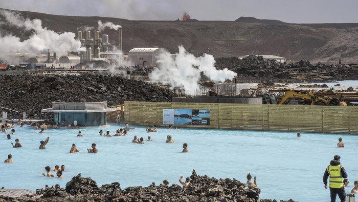 The Blue Lagoon with people bathing in it as the volcanic crater spews lava in the background in Grindavik, Iceland, Sunday, June 2, 2024. The popular Blue Lagoon geothermal spa, one of Iceland’s biggest tourist attractions in the country's southwest, was reopened Sunday after authorities said a nearby volcano had stabilized after erupting four days earlier. (AP Photo/Marco di Marco)
